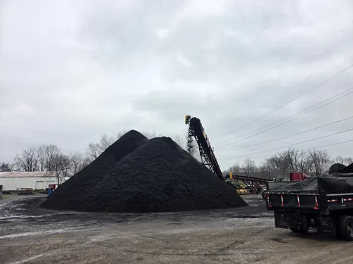 Bulk mulch pile and conveyor at the supply yard with a dump truck loading