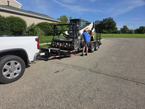 Track loader loaded on a trailer behind a pickup on a residential street