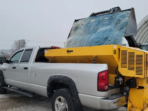 Pickup fitted with a yellow salt spreader in the equipment shop