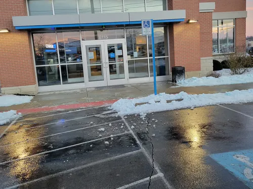 Cleared and salted sidewalk and parking spaces outside a commercial storefront after a snowfall